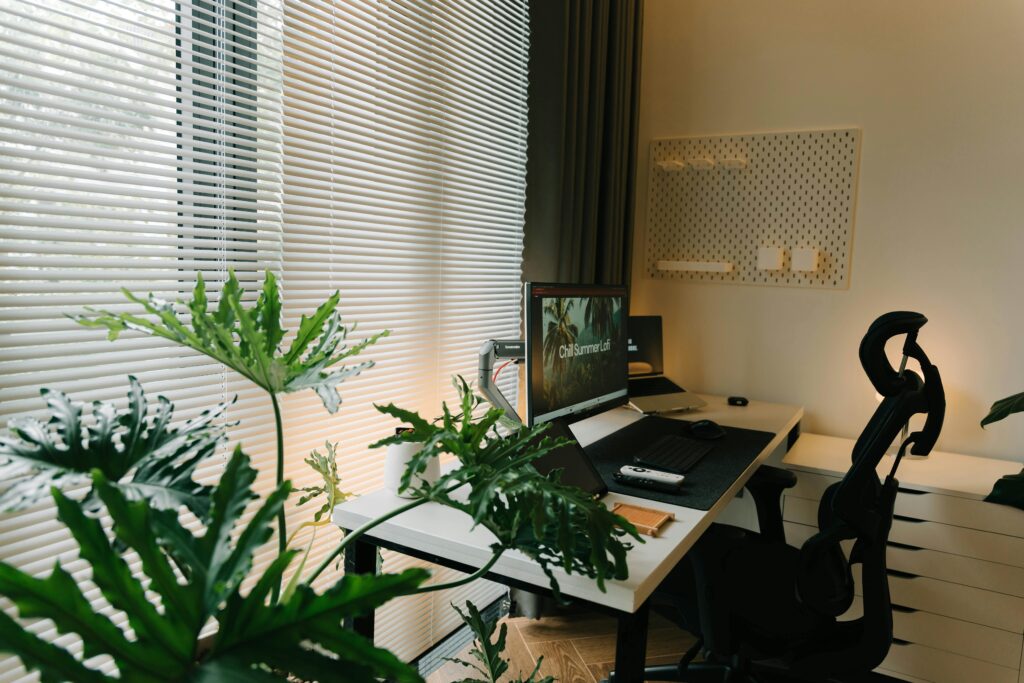 pexels-photo-28461033-28461033 A stylish home office with a desk, chair, and lush green plants near a window with blinds.