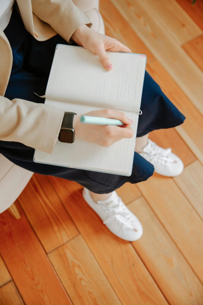 pexels-photo-3958397-3958397 High-angle view of an adult writing notes in a notebook during a therapy session.